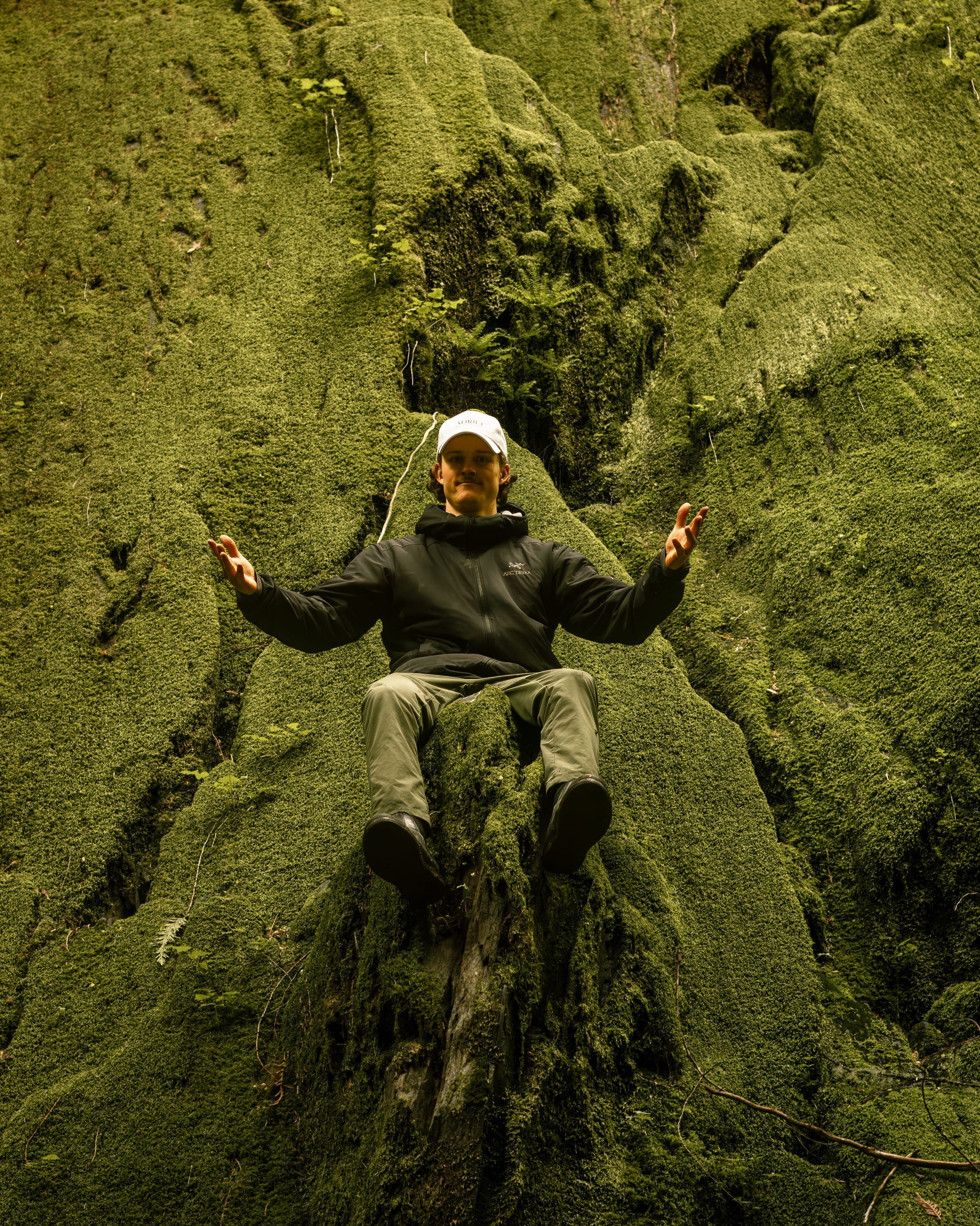 Jake Tchida sitting among mossy old-growth cedar